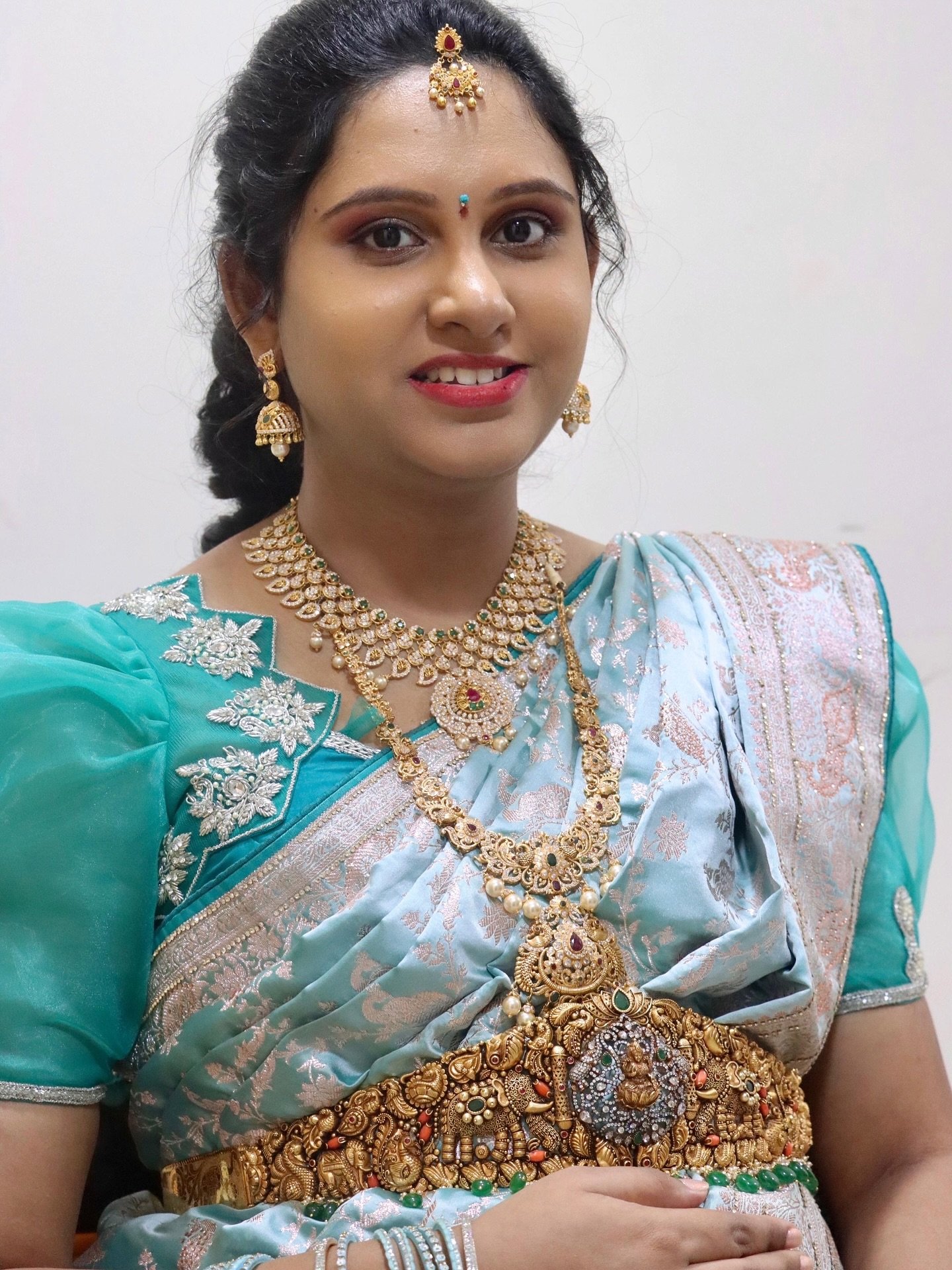 Bride in a teal-green saree with layered diamond necklaces